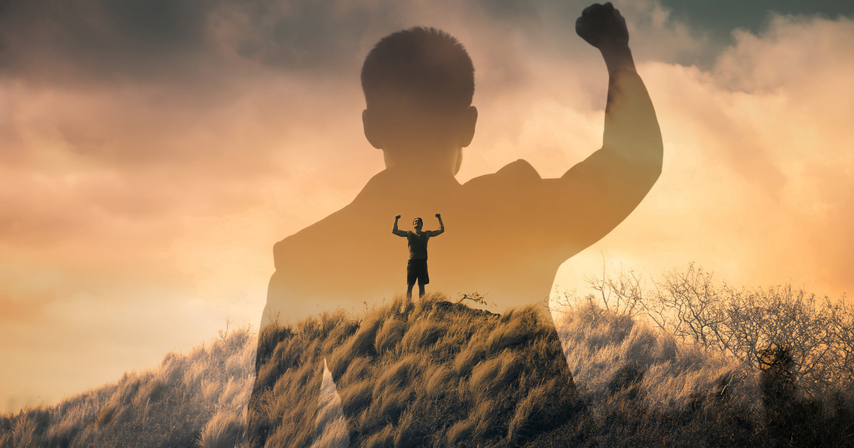 A man stands on a hill, arms raised in triumph, symbolizing overcoming life's challenges.