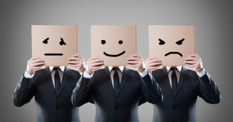 Three individuals in suits holding cardboard boxes in front of their faces with different expressions drawn on them: sad, happy, and angry, against a grey background reflecting Emotional Triggers.