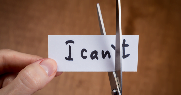 A person cutting a piece of paper that says "I can't" indicating Self-sabotage and Limiting his potential with negative self-beliefs.