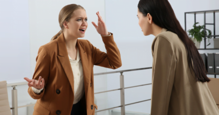 Two women engaged in a heated argument in an office setting, reflecting the presence of toxic positivity.