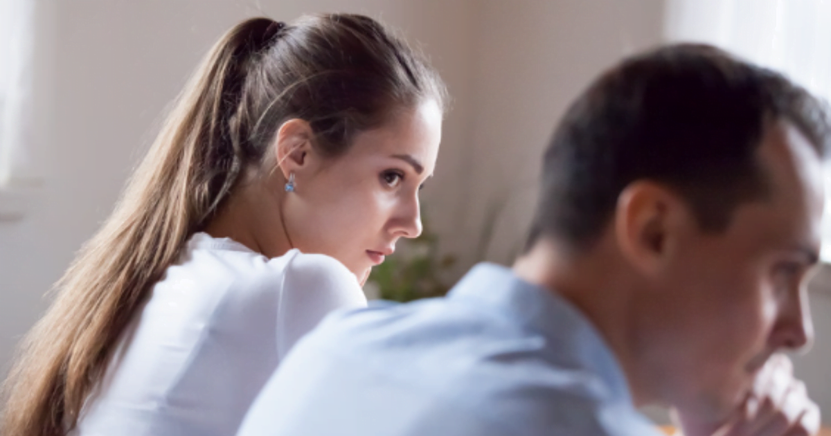 A couple engaged in intense conversation, their eyes locked, as they sit across each other at a table reflecting Walking on Eggshells.