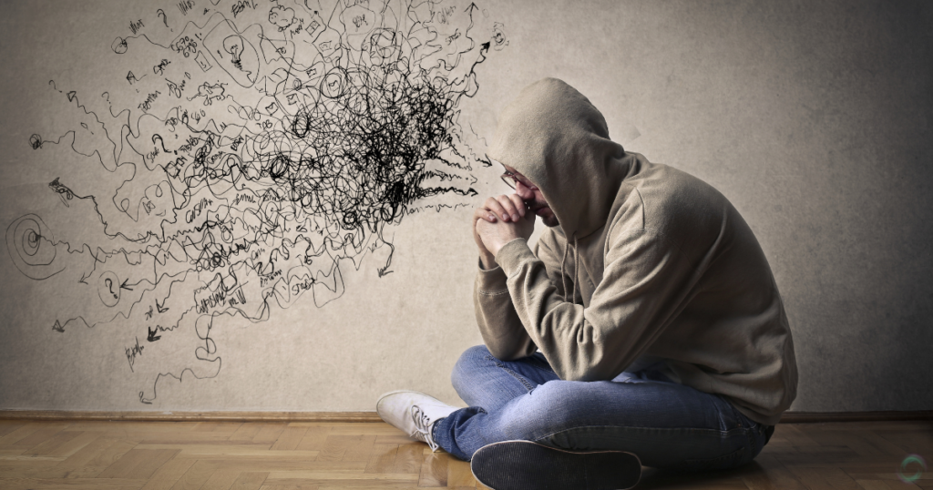 a man sitting on the floor with his hands together showing signs of negative thinking